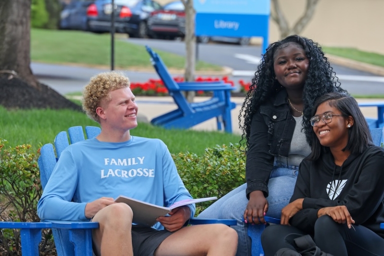 Three students hanging out in a campus plaza while studying