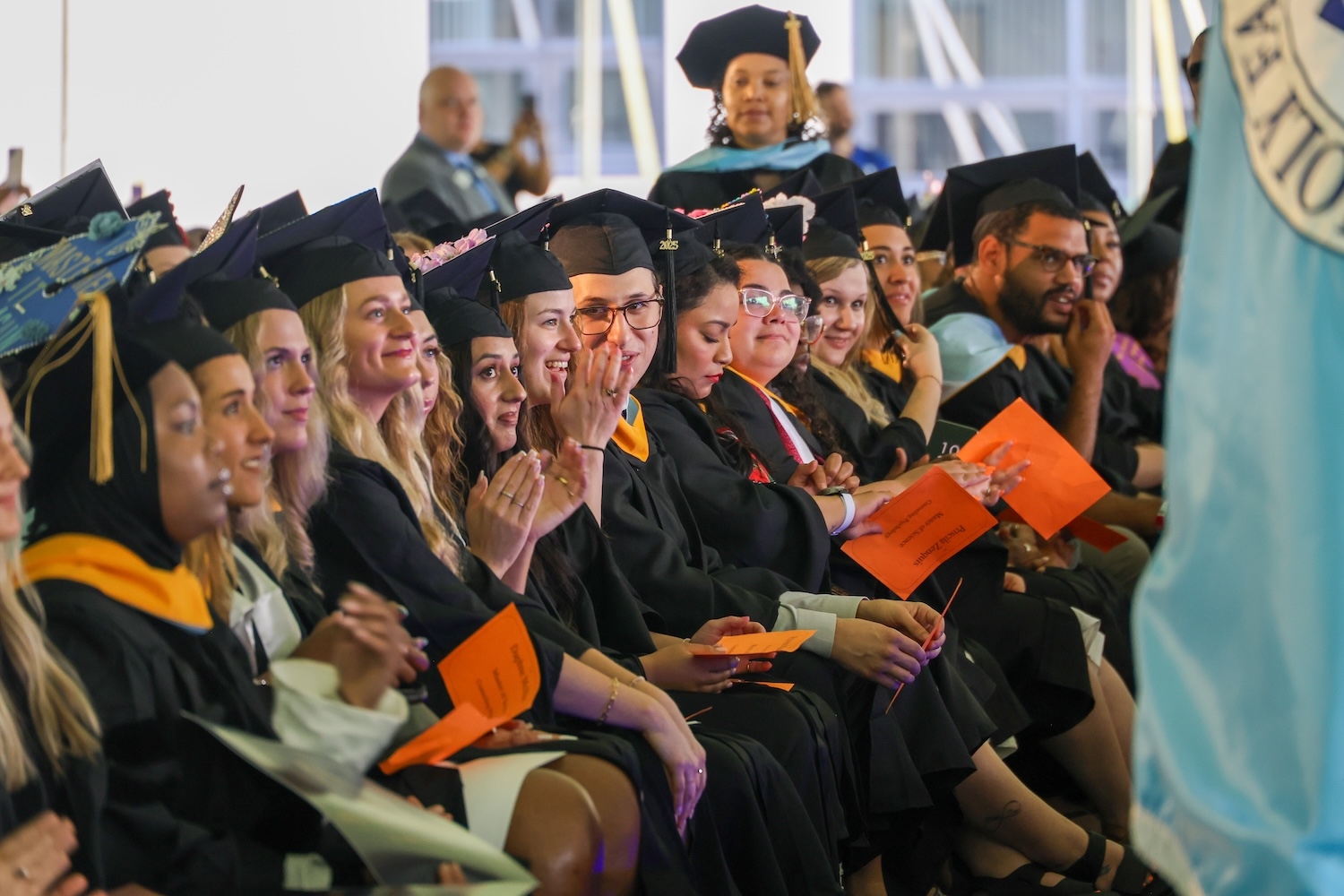 Students sitting in caps and gowns in the front row of the commencement ceremony