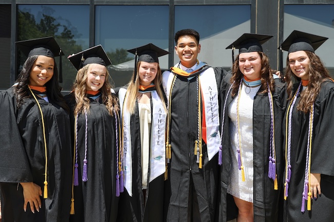 A group of new graduates pose for a photo after commencement