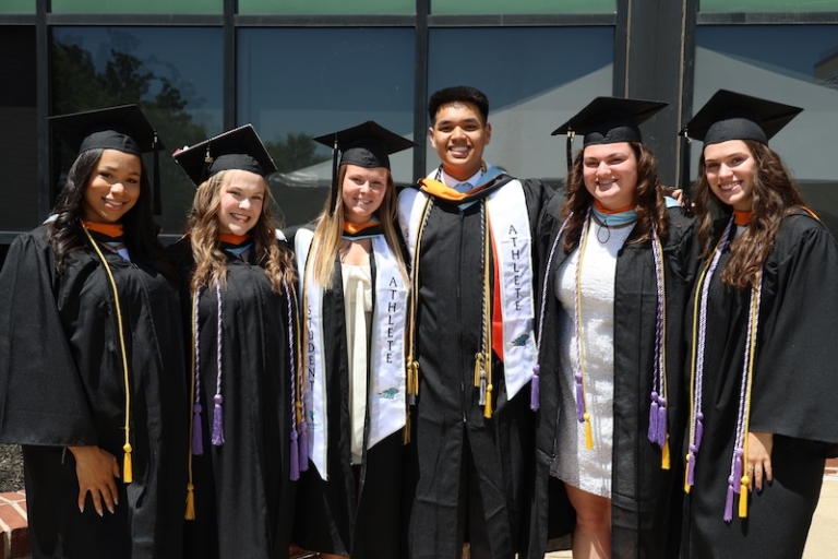 Six students in robes celebrate their graduation from Holy Family