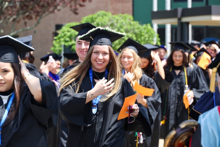 A procession of students smiling and walking out of graduation ceremony