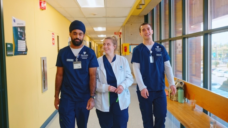 Three HFU students in scrubs walking down a hospital corridor
