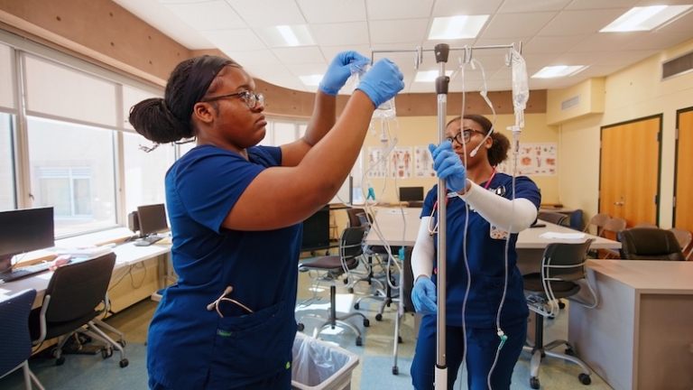 Two nursing students in the lab preparing an I.V.