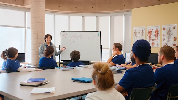 A nursing professor at a white board instructing a classroom of students