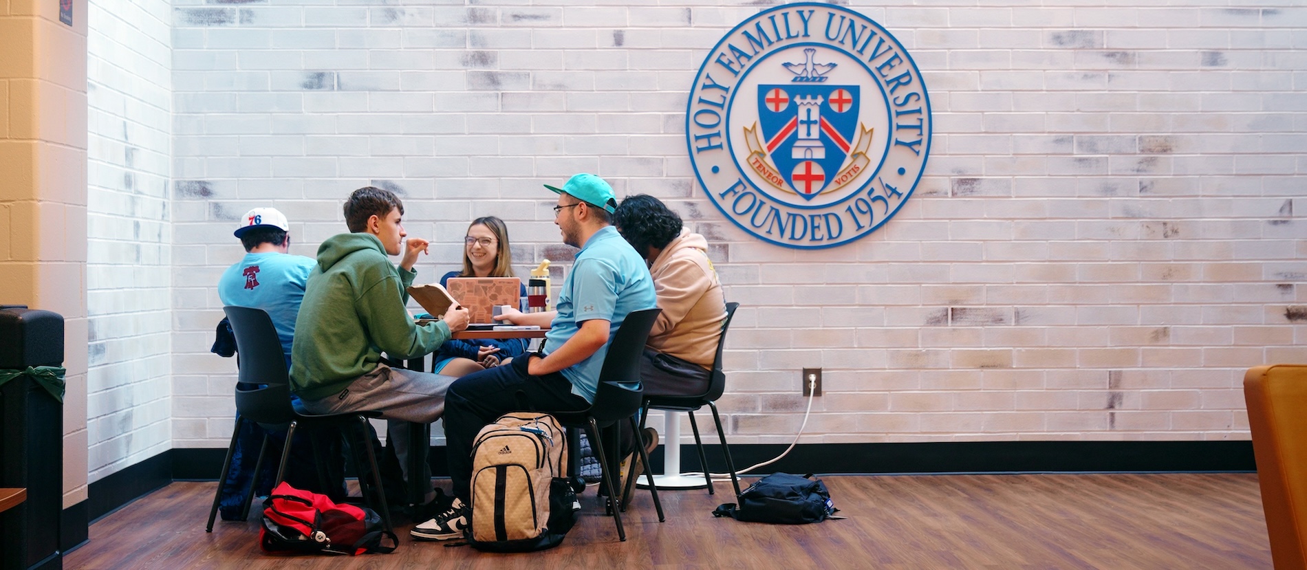 Five students sitting together and talking at a table in the Campus Center