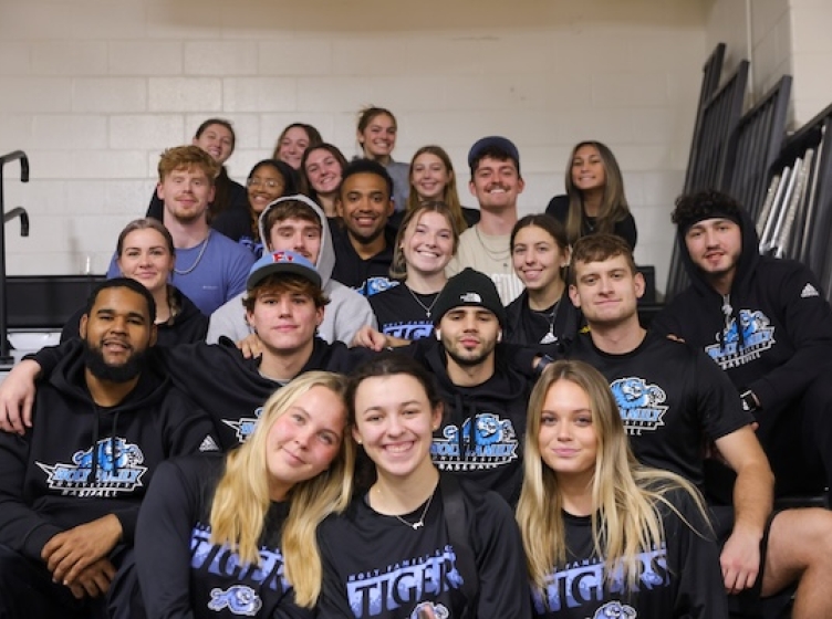 A large group of students sitting in the bleachers of a sporting event on campus
