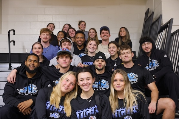 A large group of students sitting in the bleachers of a sporting event on campus