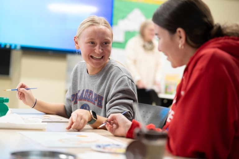 Two students smiling while working on an Education project in class