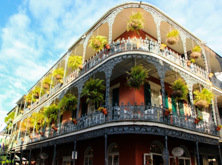 An iconic New Orleans building with hanging plants along a large balcony