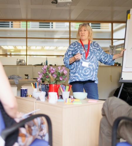 Woman in an office in front of a whiteboard training several colleagues