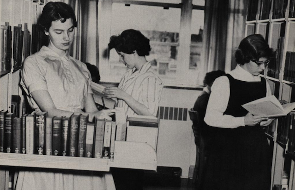 Archival black & white image from a Familogue yearbook of three female students in the library